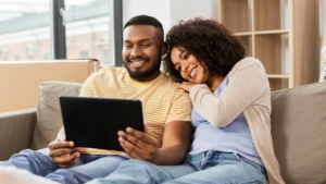 Happy couple sitting on the couch looking at an iPad